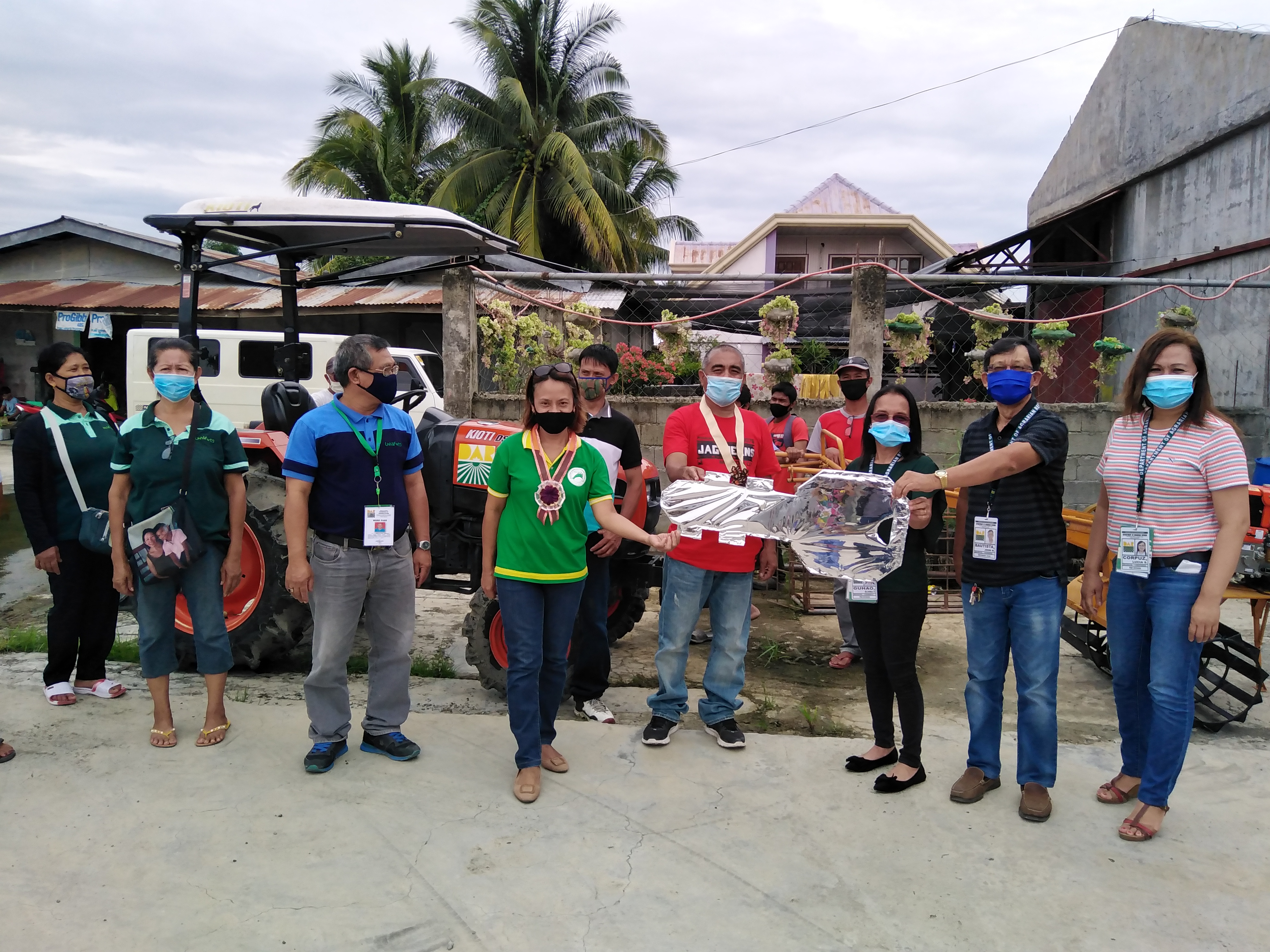 The key of responsibility on Hand Tractor with Trailer handed-over to the Chairperson of Dujali Free Farmers Multi-Purpose Cooperative (DUFFAMCO), Ernesto Nobleza, center in red shirt, together with the coop’s Manager Gemma Bacurayo in green shirt. Also in the picture are from right, Luz Corpuz, PBDD ARPO 1, B.E. Dujali MARPO John Bautista, PBDD-EDES Section Chief Elvira Guhao, B.E. Dujali SARPT Bernardo Lavilla and some of the members of the cooperative.